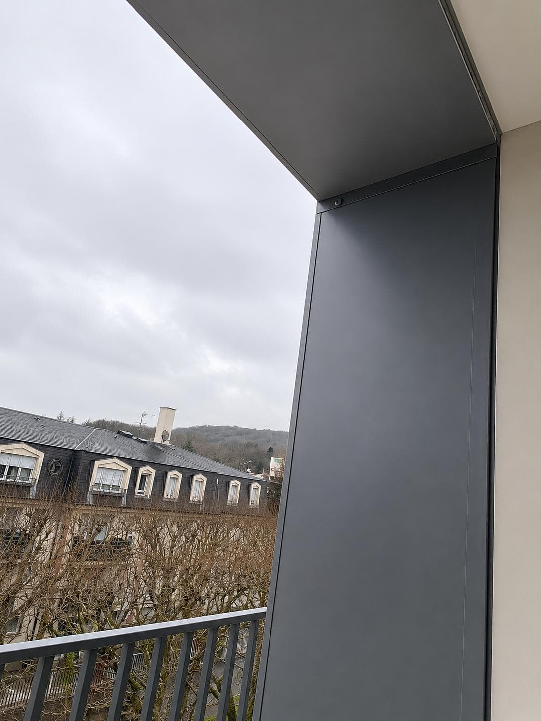 Habillage d'angle en tôle laquée gris anthracite dans le tableau d'une loggia.